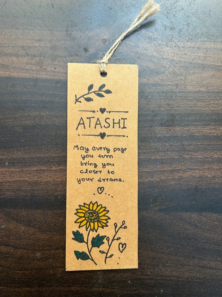 The handmade bookmark, front side — Atashi’s name and a sunflower.