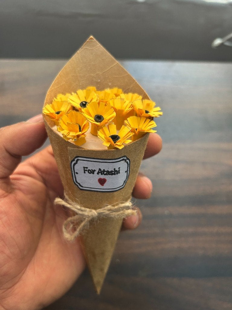 A handmade paper bouquet of folded flowers, tied in jute twine.