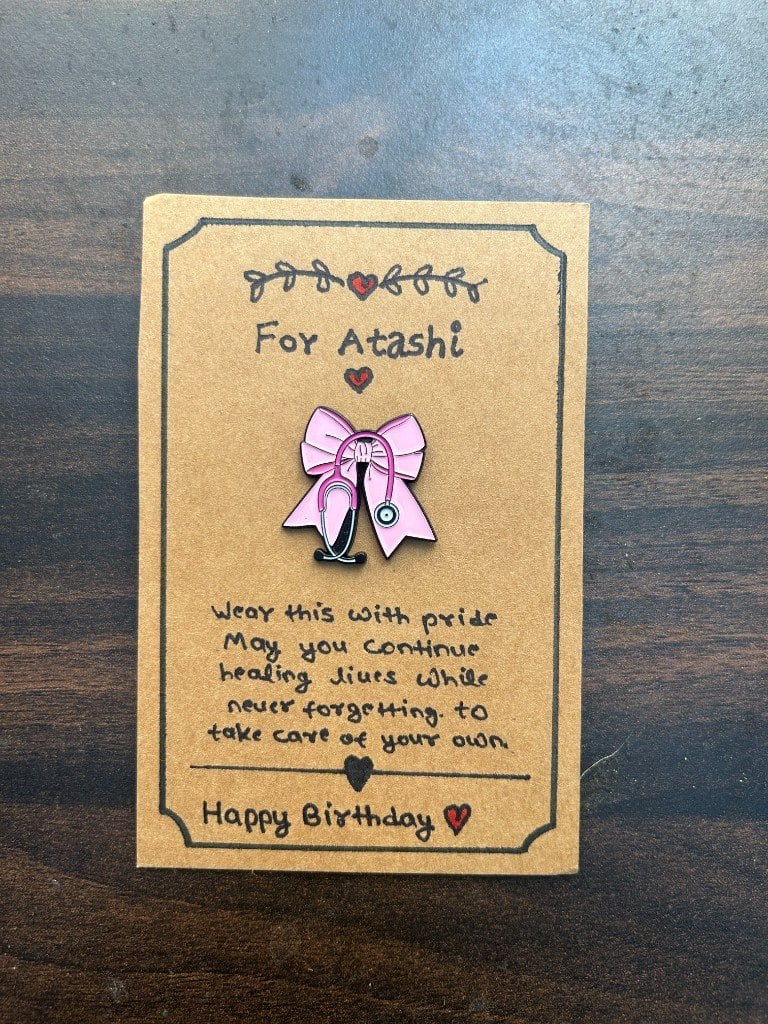 A small handmade doctor pin, presented on its card.